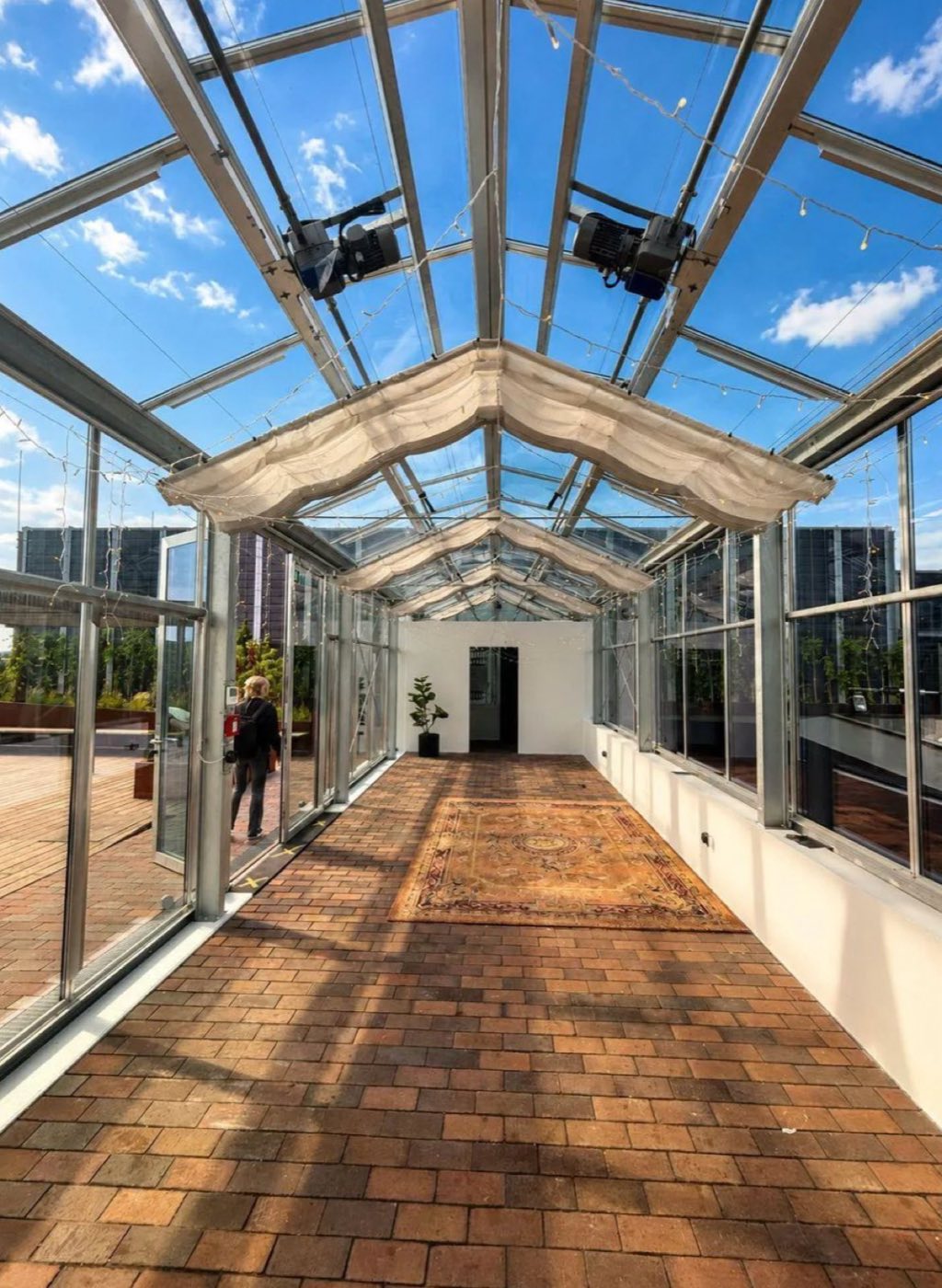 Inside the glass Pavilion, a covered walkway with a brick floor